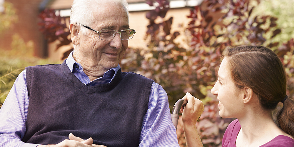 Older man sitting with younger woman outside Older man sitting with younger woman outside